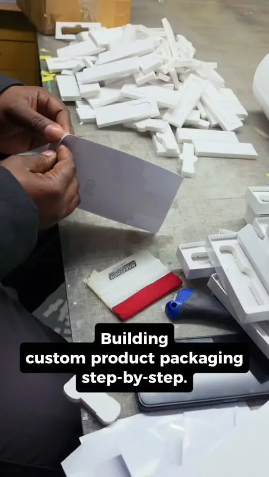 A rigid presentation box being hand-wrapped